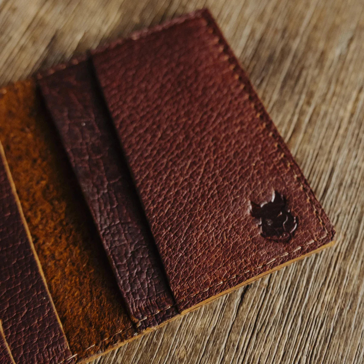 bad leather goods' wild boar wallet on a wooden table and open with a pebbled grain pattern is