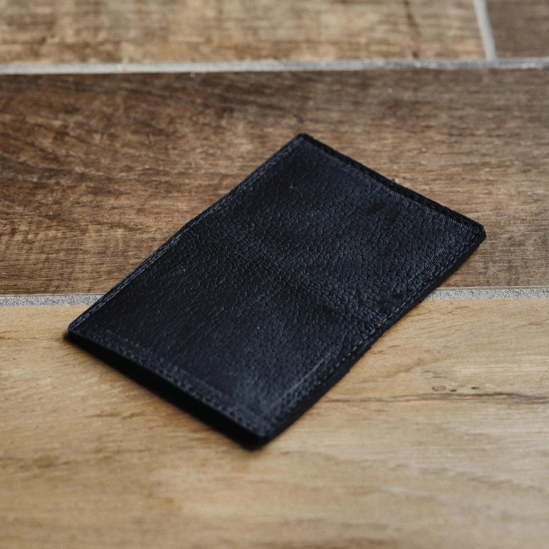 Black leather wallet on a wooden surface