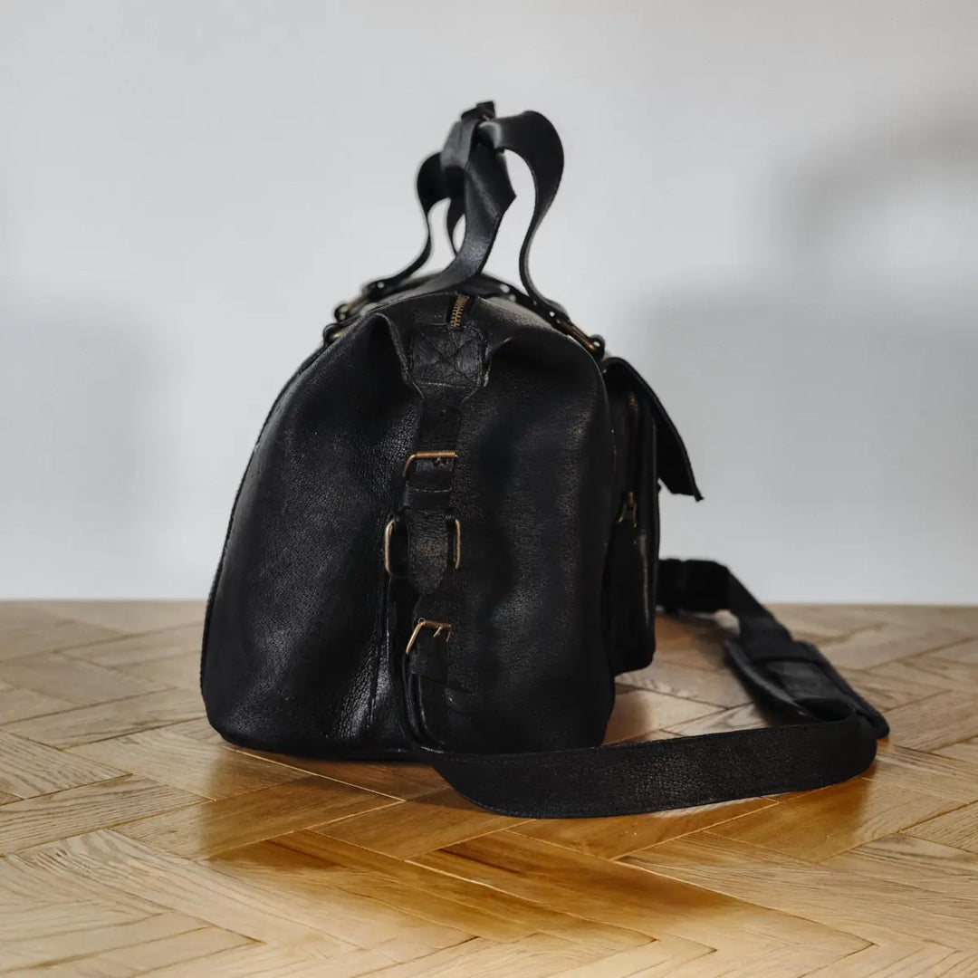 Black boar leather backpack on a wooden floor with a white wall background