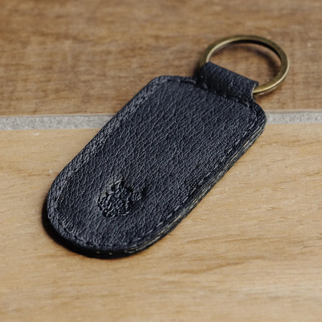 Black leather keychain with a ring on a wooden surface