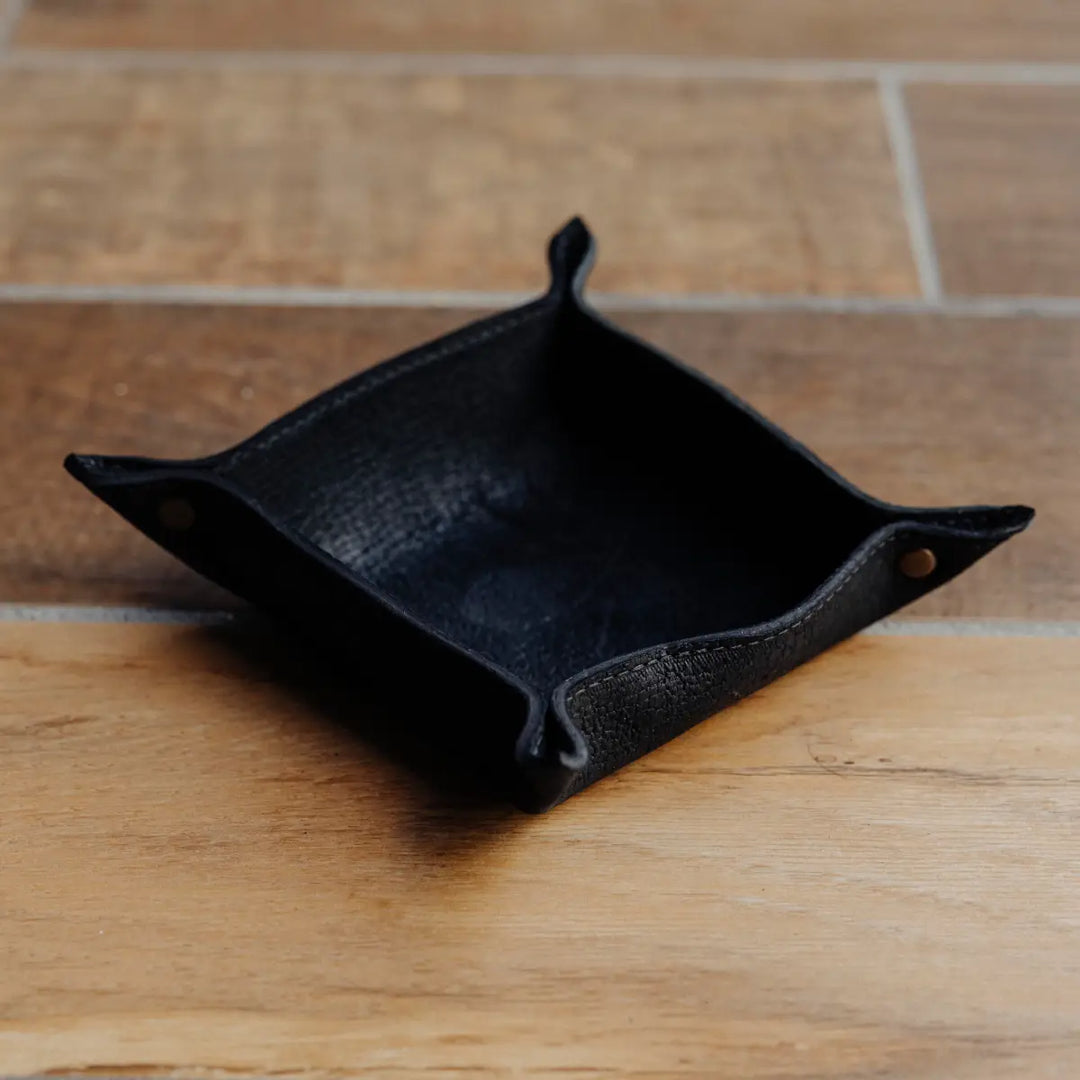 Black boar leather tray on a wooden surface