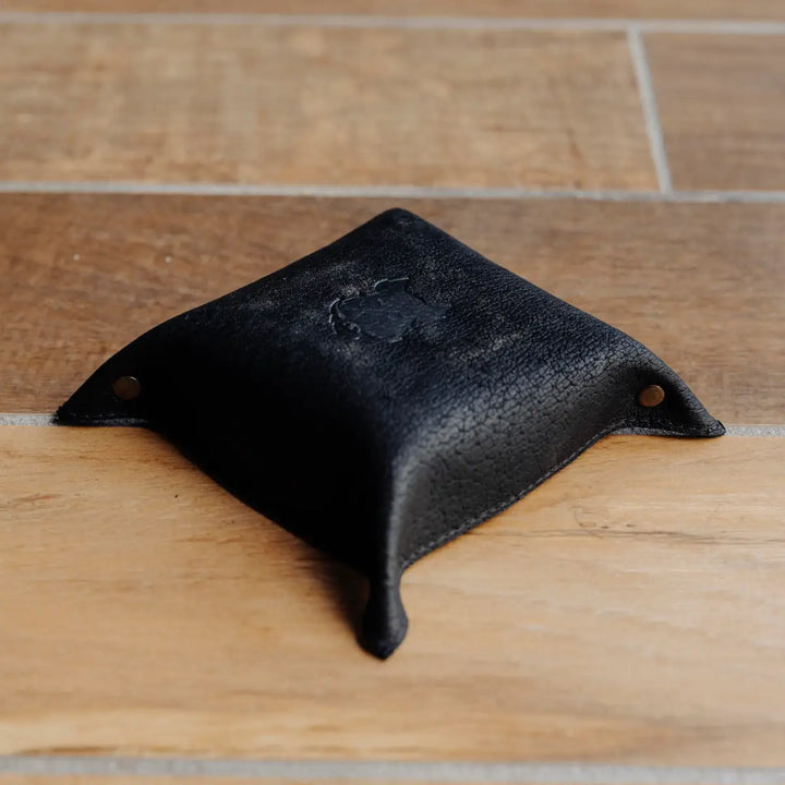 Black boar leather tray on a wooden floor