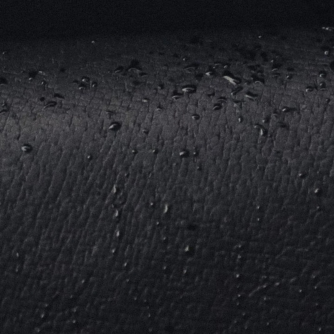 Close-up of a textured black Jabari leather surface with small raised grain and water beeding off