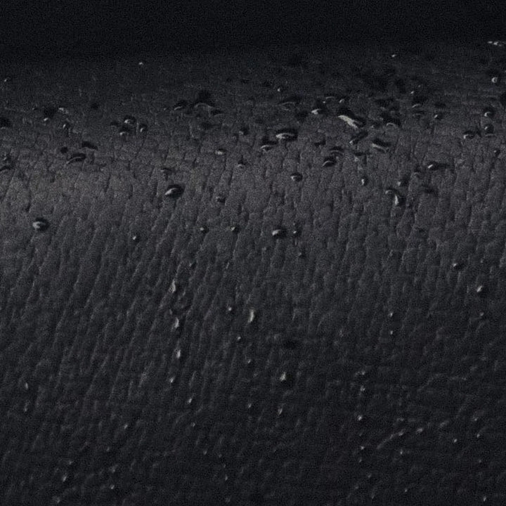 Close-up of a textured black Jabari leather surface with small raised grain and water beeding off