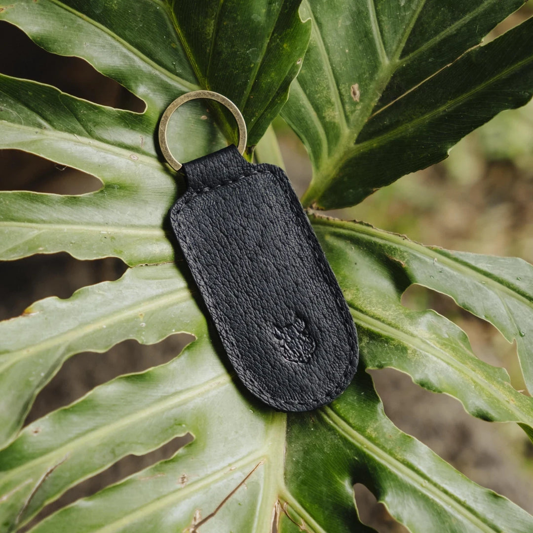 Black jabari boar leather keychain on a large green leaf