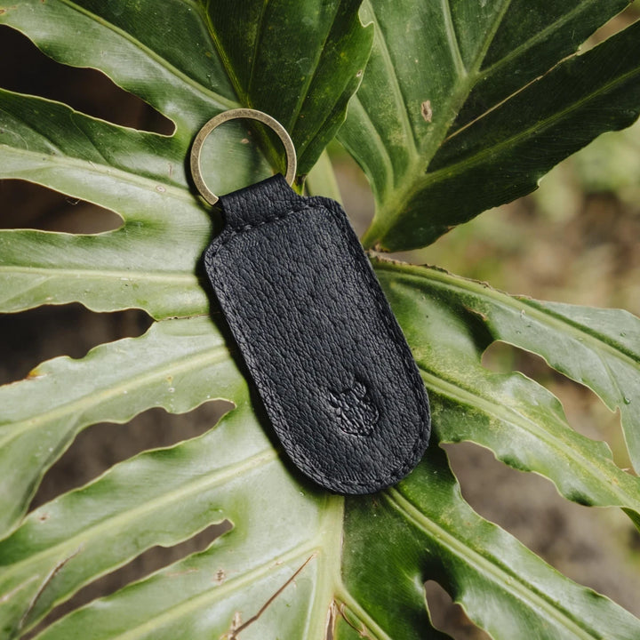 Black jabari boar leather keychain on a large green leaf