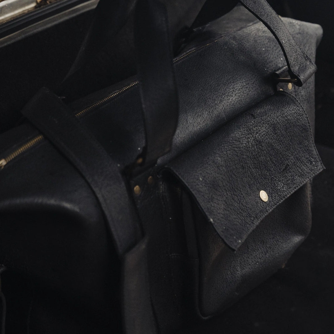 Close-up of a black jabari wild boar leather duffel bag with a dark background