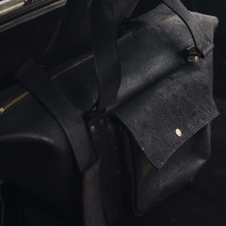Close-up of a black jabari wild boar leather duffel bag with a dark background