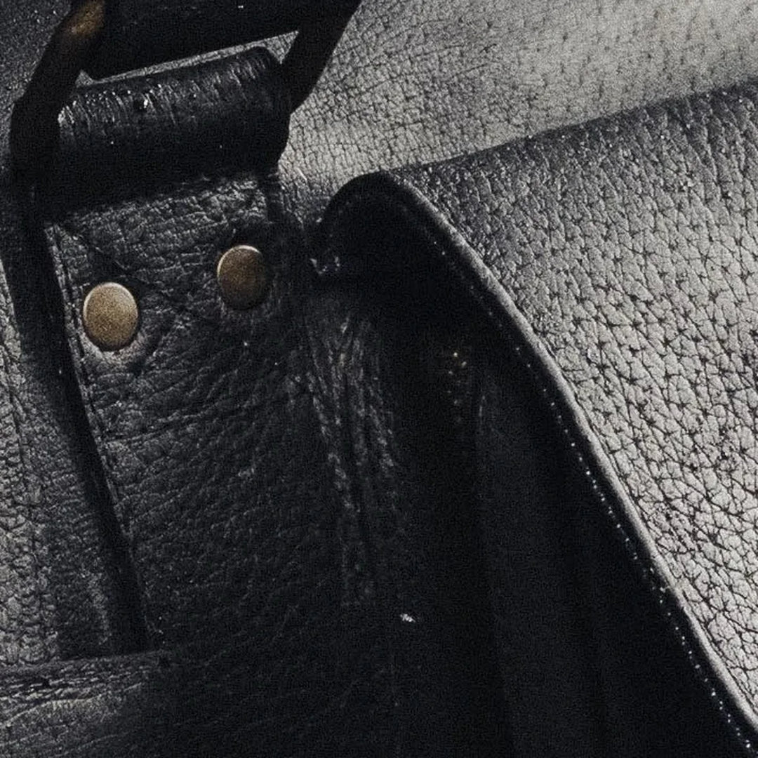 Close-up of a black boar leather duffle bag with brass rivets