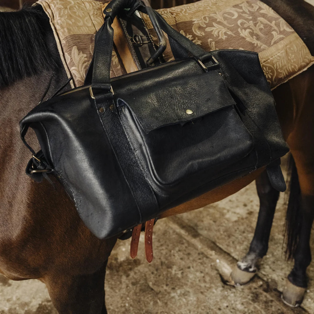 Black Jabari boar leather messenger bag on a horse with a patterned saddle