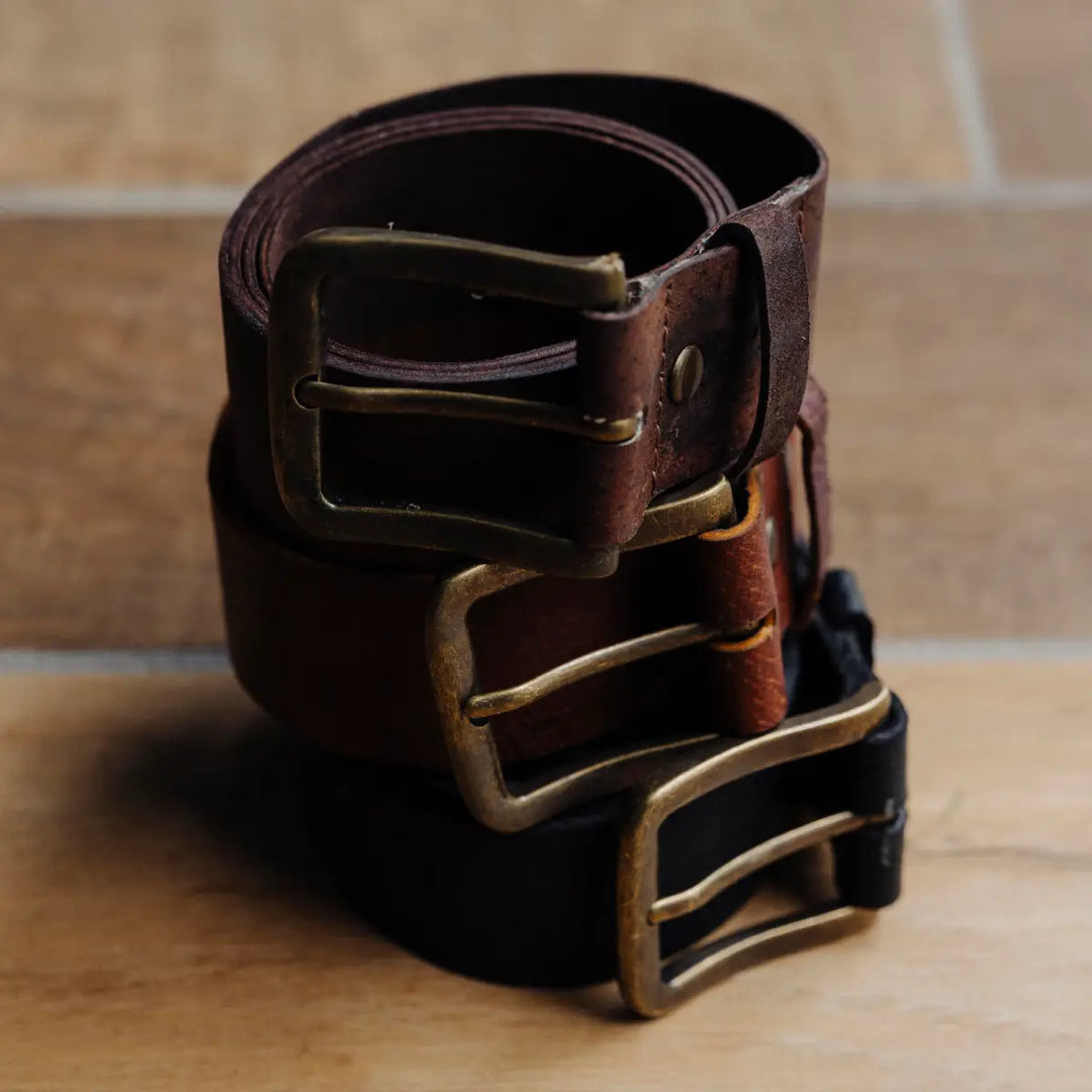 Boar leather belts with brass buckle on a wooden surface