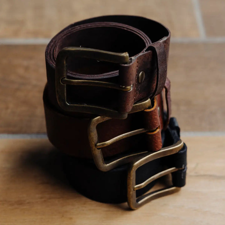 Boar leather belts with brass buckle on a wooden surface