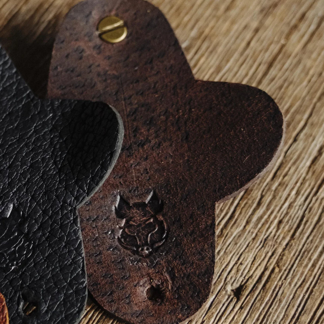 Close-up of a brown leather cord wrap with a metal fastener on a wooden surface