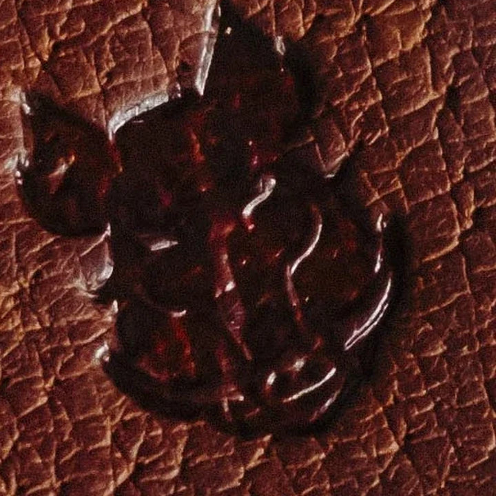 Close-up of a dark brown leather texture with a Bad Leather Goods logo.