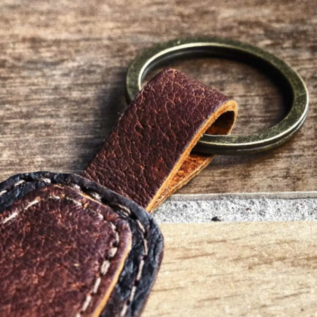 Brown leather keychain with a metal ring on a wooden surface