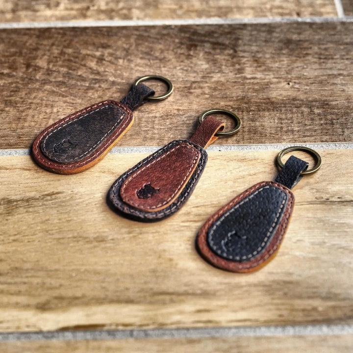 Three leather keychains on a wooden surface
