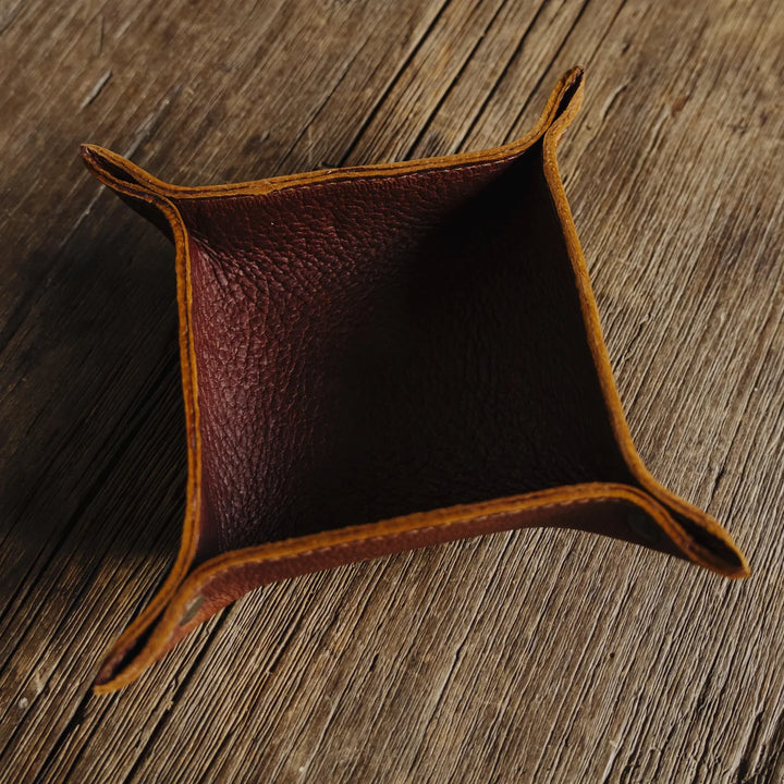 Brown leather catch-all valet tray on a wooden surface