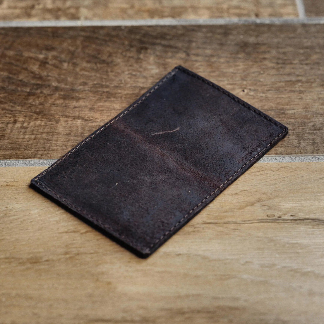 Dark brown leather wallet on a wooden surface