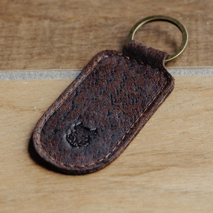 Brown boar leather keychain with a metal ring on a wooden surface