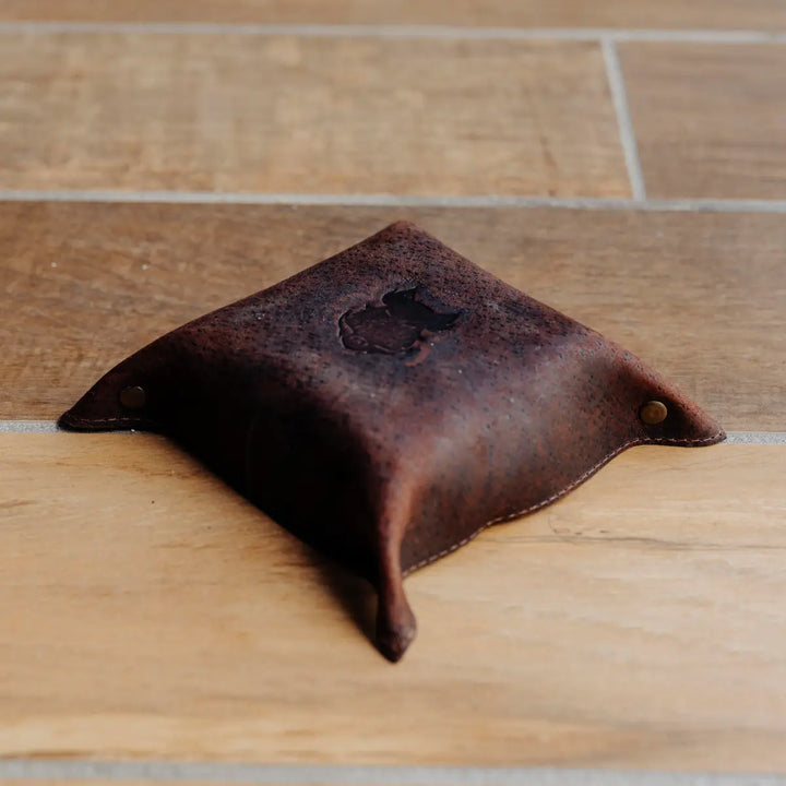 Dark brown boar leather tray with a Bad Leather Goods boar brand on a wooden surface