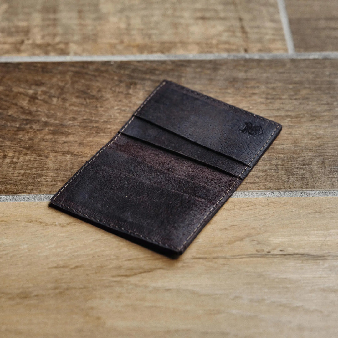 Dark brown leather wallet on a wooden surface