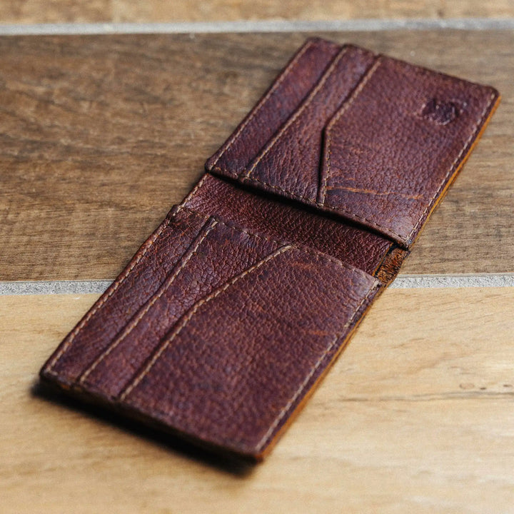 Reddish brown leather wallet on a wooden surface