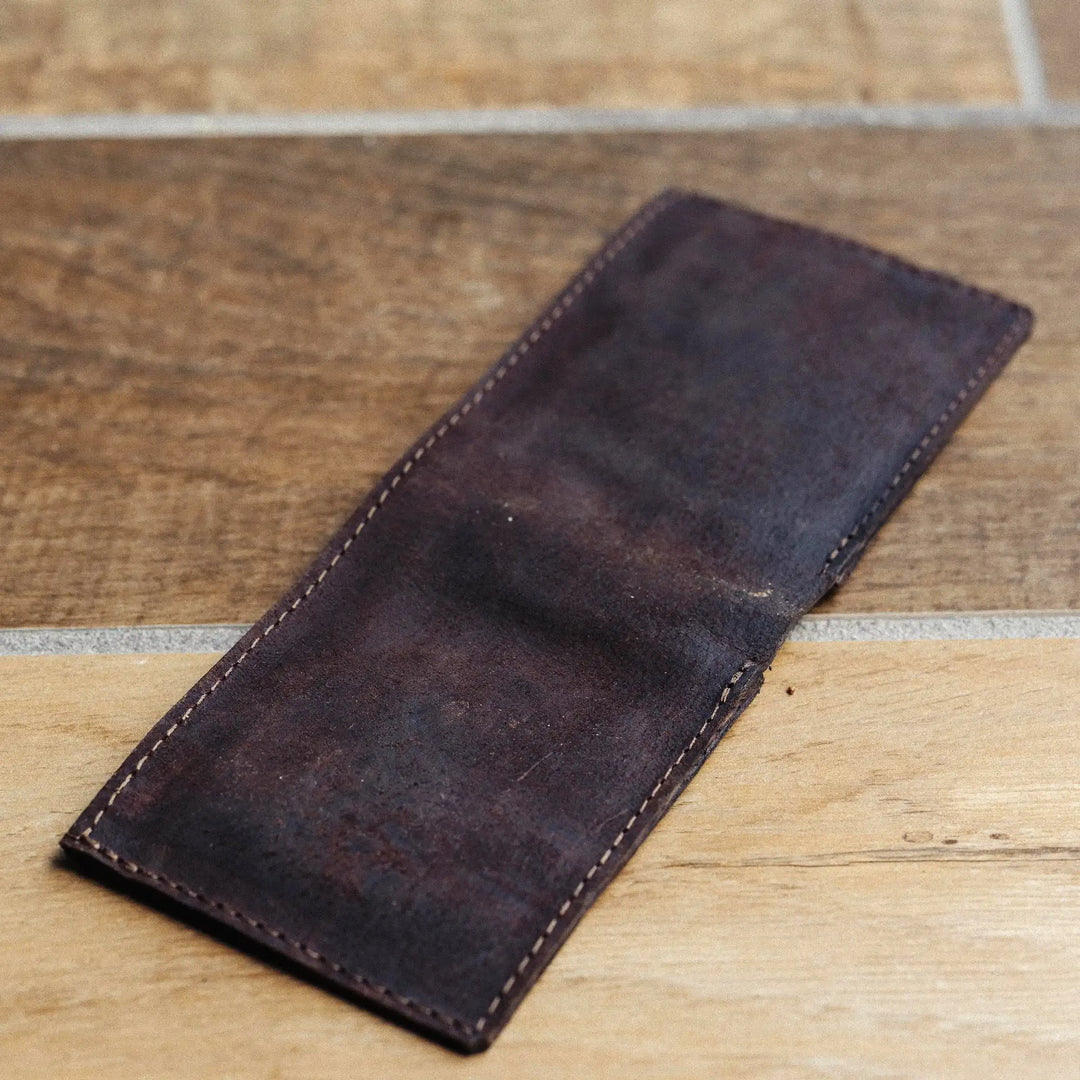 Dark brown leather wallet on a wooden surface