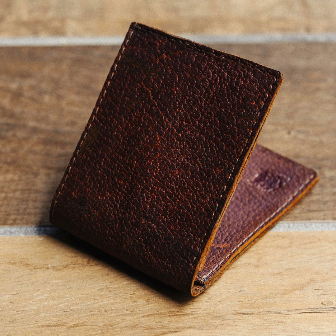 Reddish brown leather wallet on a wooden surface