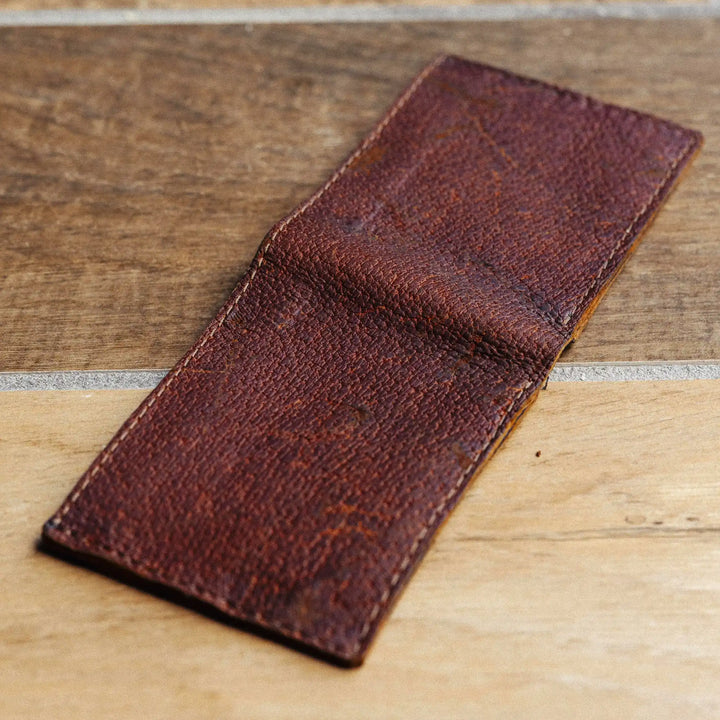Reddish brown leather wallet on a wooden surface