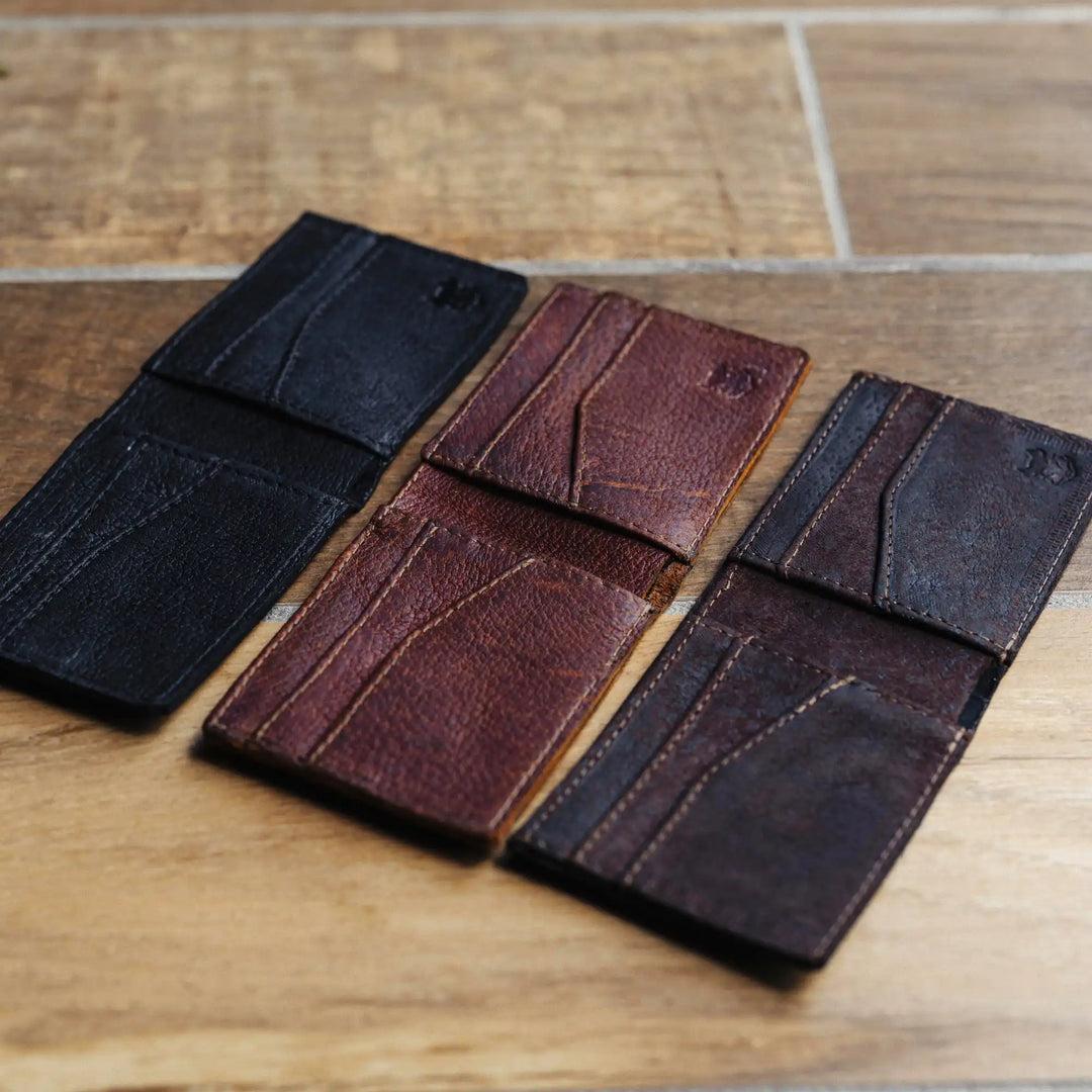 Three leather wallets in black, brown, and dark brown on a wooden surface
