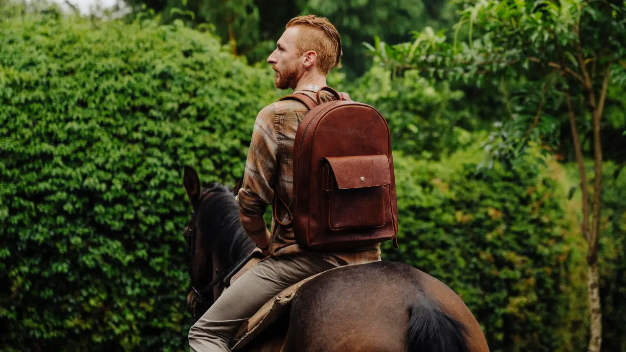 Man riding a horse wearing a brown  boar leather backpack with a forest background
