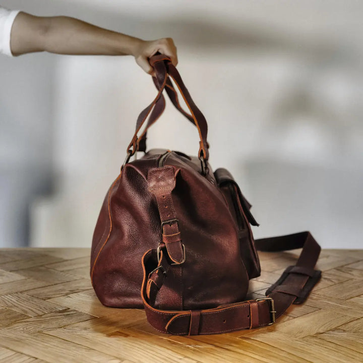 Cognac boar leather bag on a wooden surface with a blurred background