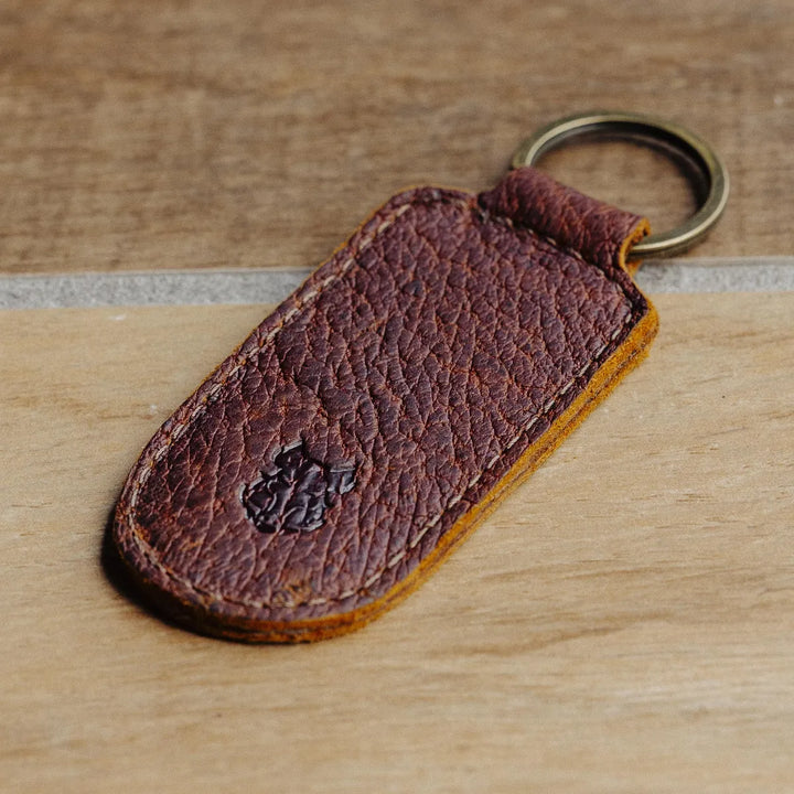 Brown leather keychain with a metal ring on a wooden surface