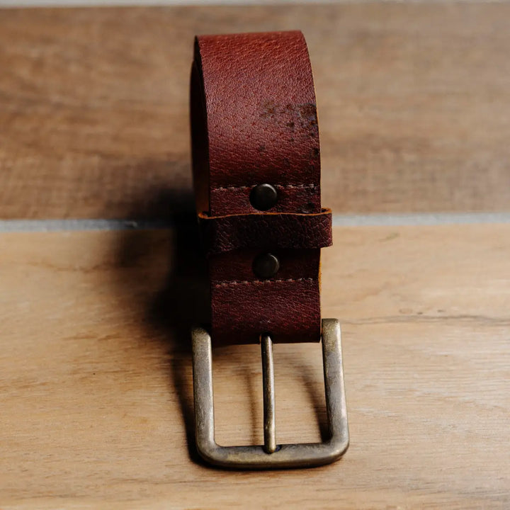 Brown cognac jabari leather belt with a silver buckle on a wooden surface
