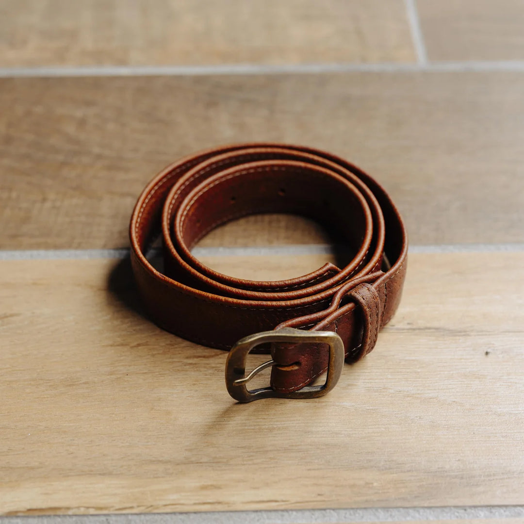 Brown leather belt with a gold buckle on a wooden surface