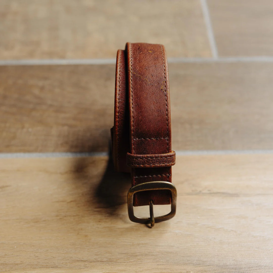 Brown leather belt on a wooden surface