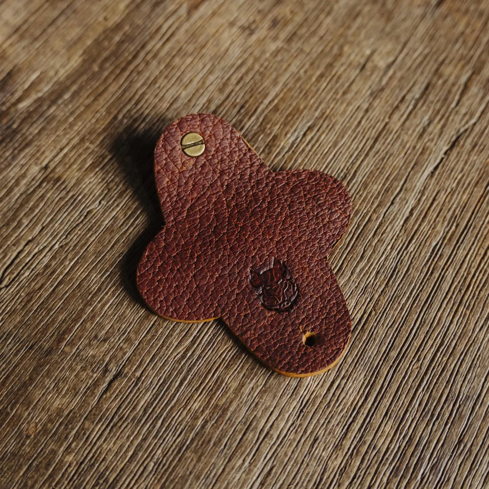 Brown cognac Jabari boar leather cord wrap with a brass screw on a wooden surface