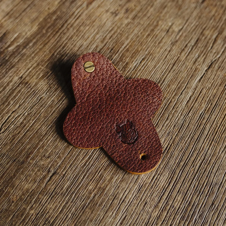 Brown cognac Jabari boar leather cord wrap with a brass screw on a wooden surface