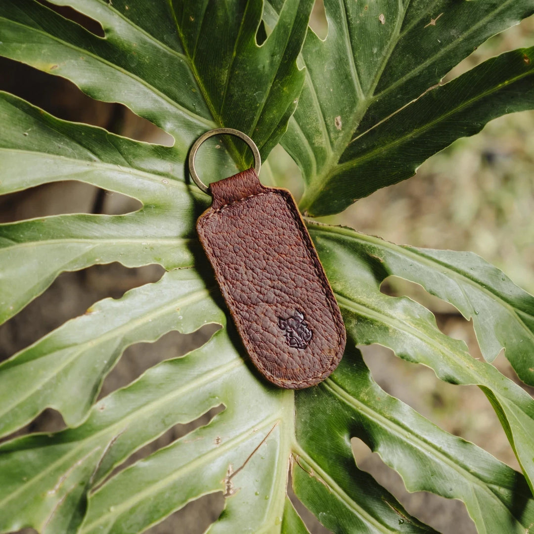 Brown cognac jabari boar leather keychain on a green leaf