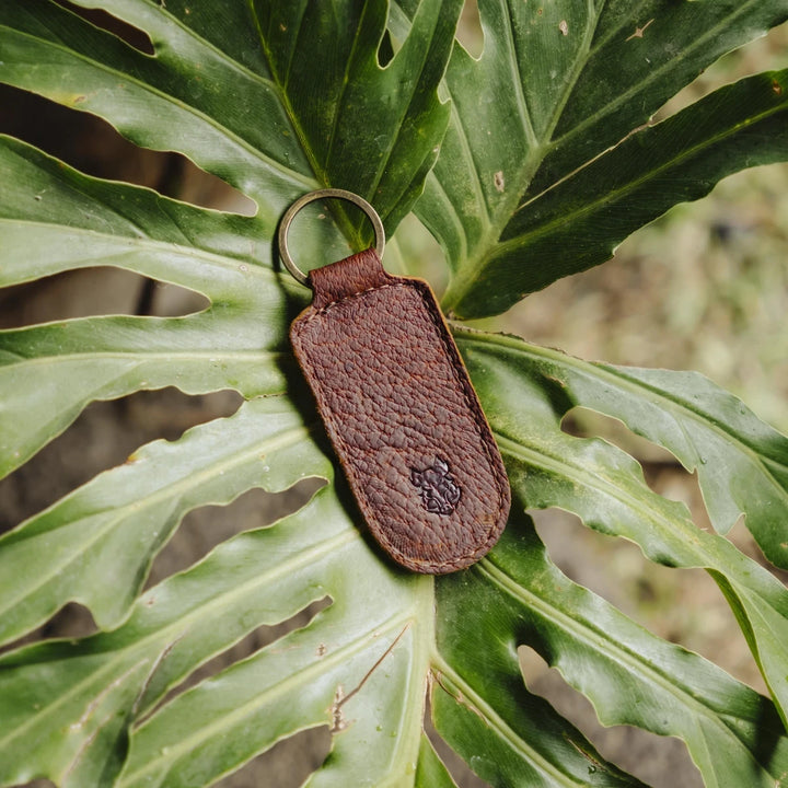 Brown cognac jabari boar leather keychain on a green leaf
