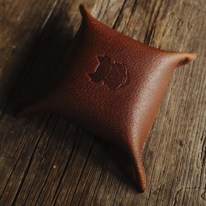 Brown cognac jabari boar leather valet with a logo on a wooden surface