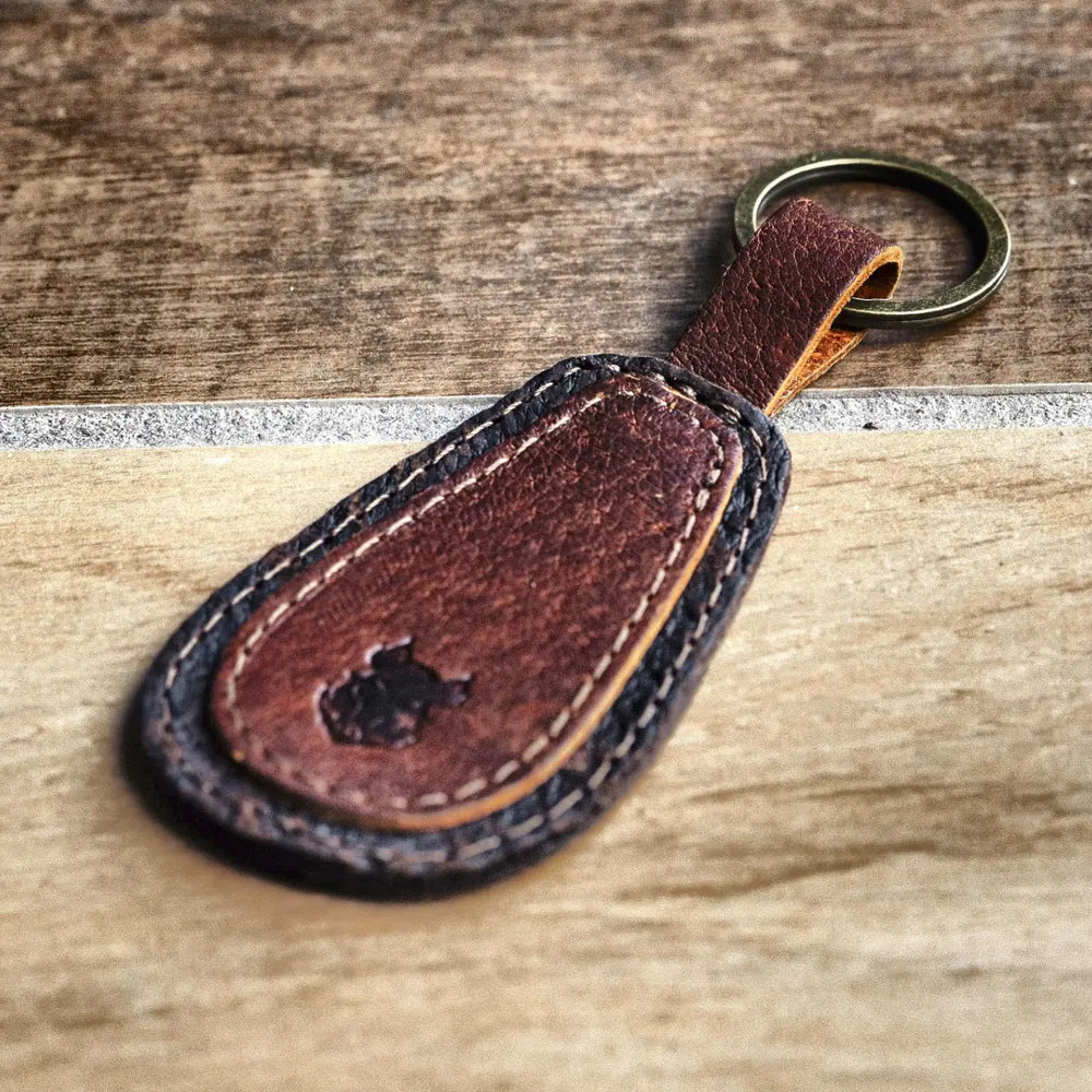 Brown leather keychain with a key ring on a wooden surface