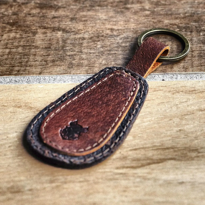 Brown leather keychain with a key ring on a wooden surface