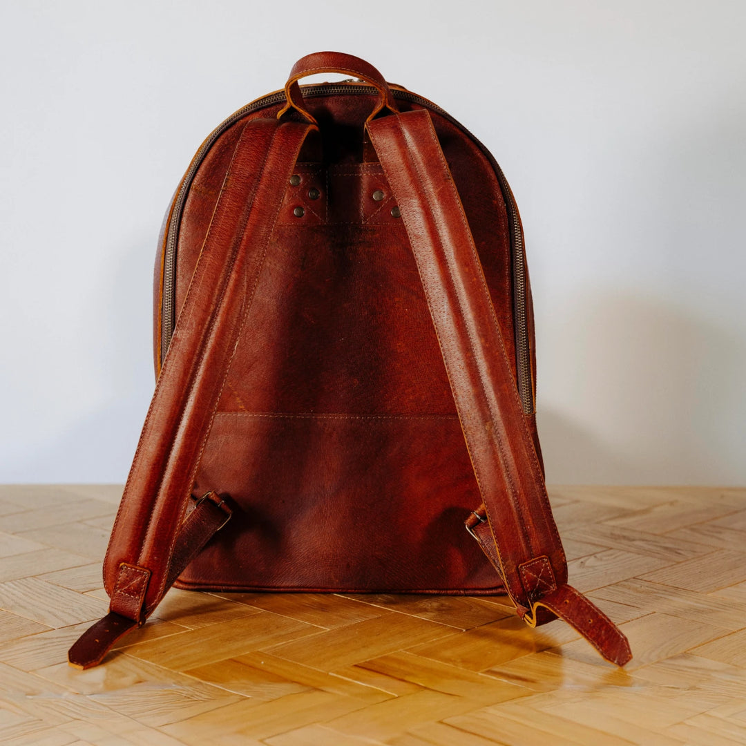 A brown leather backpack on a wooden surface
