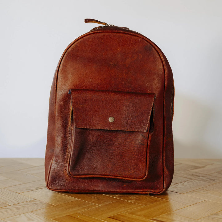 Brown boar leather backpack on a wooden surface with a white background