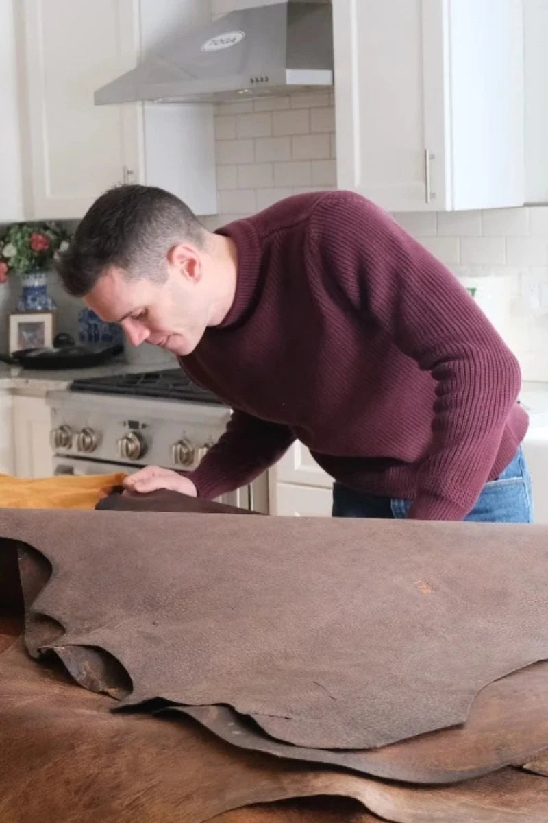 Man in a kitchen rolling out boar leather on a table