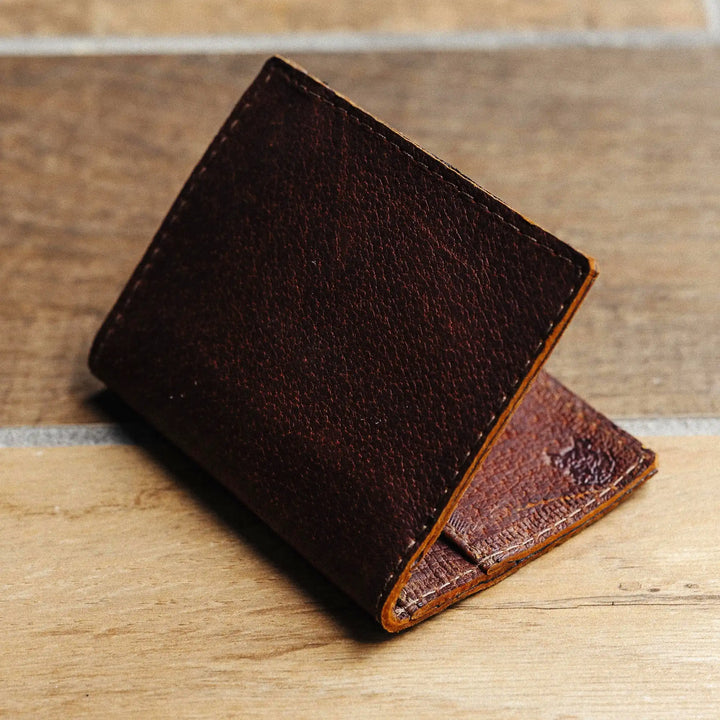 reddish brown leather wallet on a wooden surface