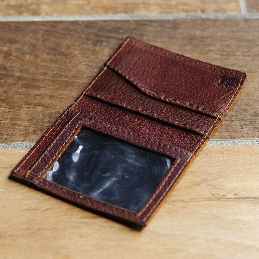 reddish brown leather wallet on a wooden surface