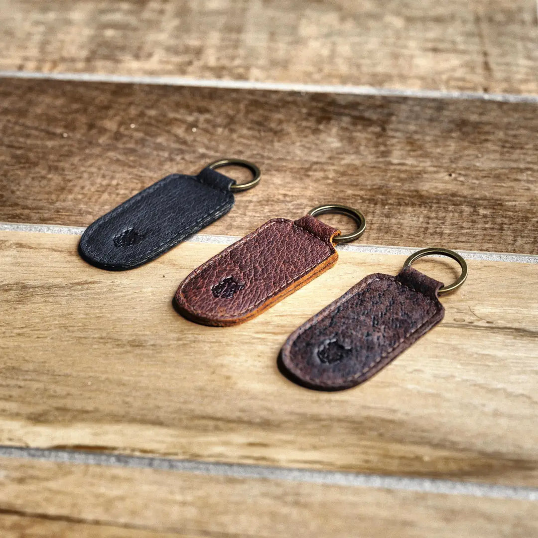 Three leather keychains on a wooden surface