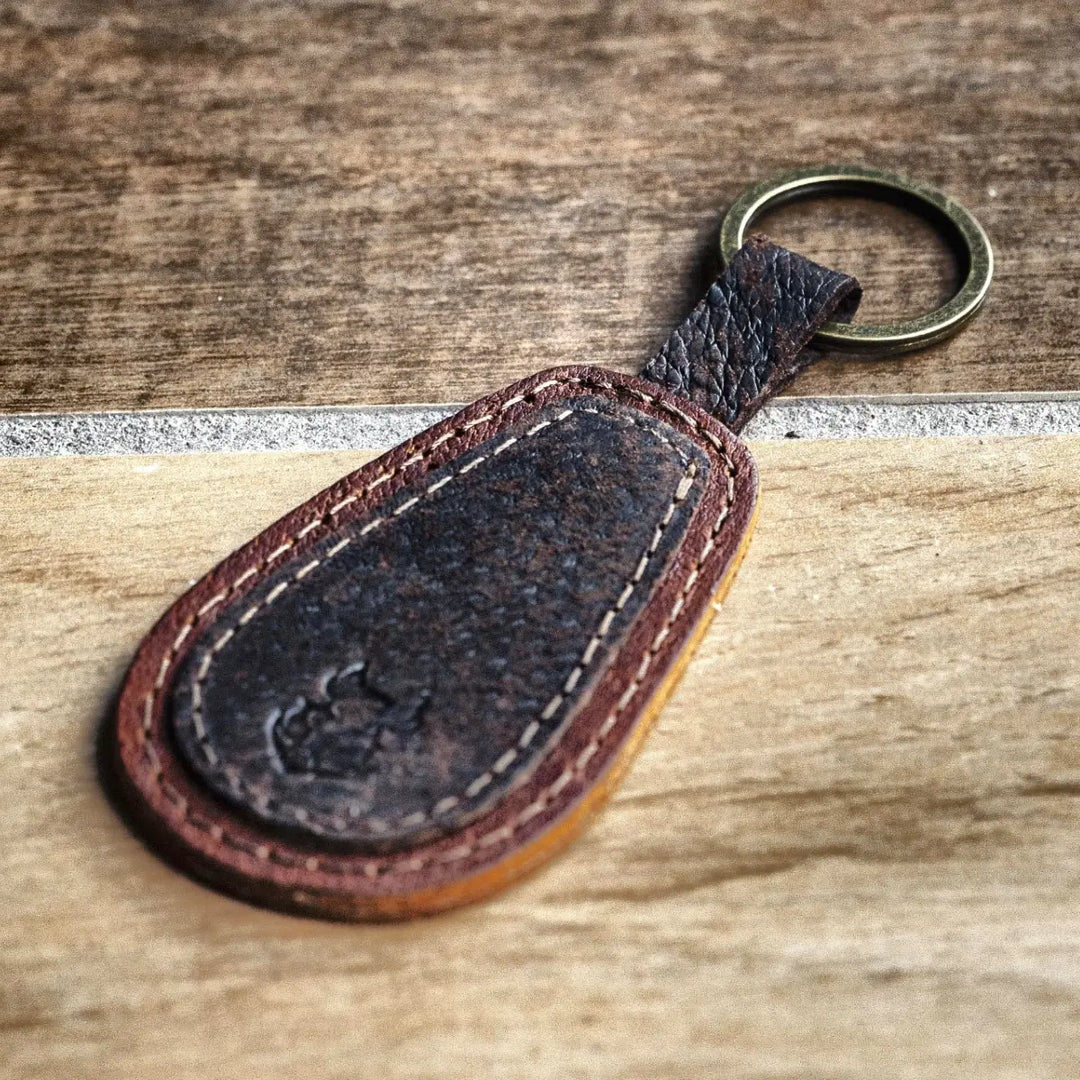 Brown leather keychain with a metal ring on a wooden surface